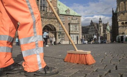 Ein Mitarbeiter von DBS reinigt die Straße am Marktplatz in Bremen mit einem Besen. | © Die Bremer Stadtreinigung