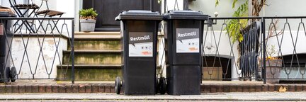 Zwei schwarze Abfalltonnen, die vor einem Reihenhaus stehen. Auf beiden Tonnen steht "Restmüll". | © Die Bremer Stadtreinigung