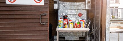 Ein geöffneter Schuppen, in dem ein Küchenwagen mit Chemikalien und Sonderstoffen steht. Auf der Schiebetür des Schuppens befinden sich Warnsymbole.  | © Die Bremer Stadtreinigung