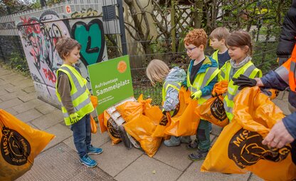 Kita Kinder bringen den gesammelten Müll zum Sammelplatz