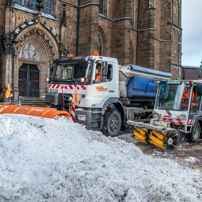 Zwei Räumungsfahrzeuge des Winterdients bilden einen Schneehaufen vor dem Eingang des Bremer Doms. Im Hintergrund ist die bereits gesäuberte Straße zu sehen. | © Die Bremer Stadtreinigung