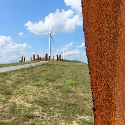Fotografie des Wegs zur Aussichtsplattform Metalhenge. | © Die Bremer Stadtreinigung Weg von der Blocklanddeponie zur Aussichtsplattform Metalhenge. Im Hintergrund sind Windgeneratoren sichtbar. | © Die Bremer Stadtreinigung