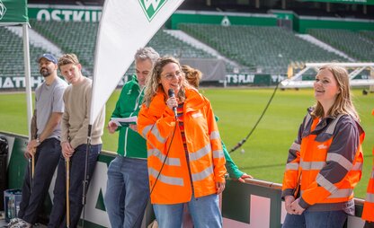 Ramona Alberts von Die Bremer Stadtreinigung spricht zu den Sammelnden im Weserstadion.