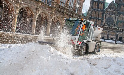 Auf dem Bremer Marktplatz fährt ein Räumungsfahrzeug des Winterdients durch einen Schneehaufen und macht die Straße wieder frei. | © Die Bremer Stadtreinigung