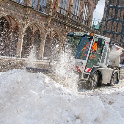 Auf dem Bremer Marktplatz fährt ein Räumungsfahrzeug des Winterdients durch einen Schneehaufen und macht die Straße wieder frei. | © Die Bremer Stadtreinigung